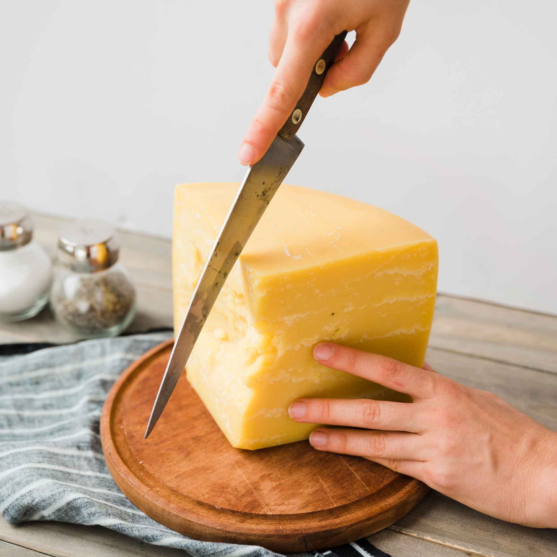 persona cortando queso semiblando con cuchillo alargado 